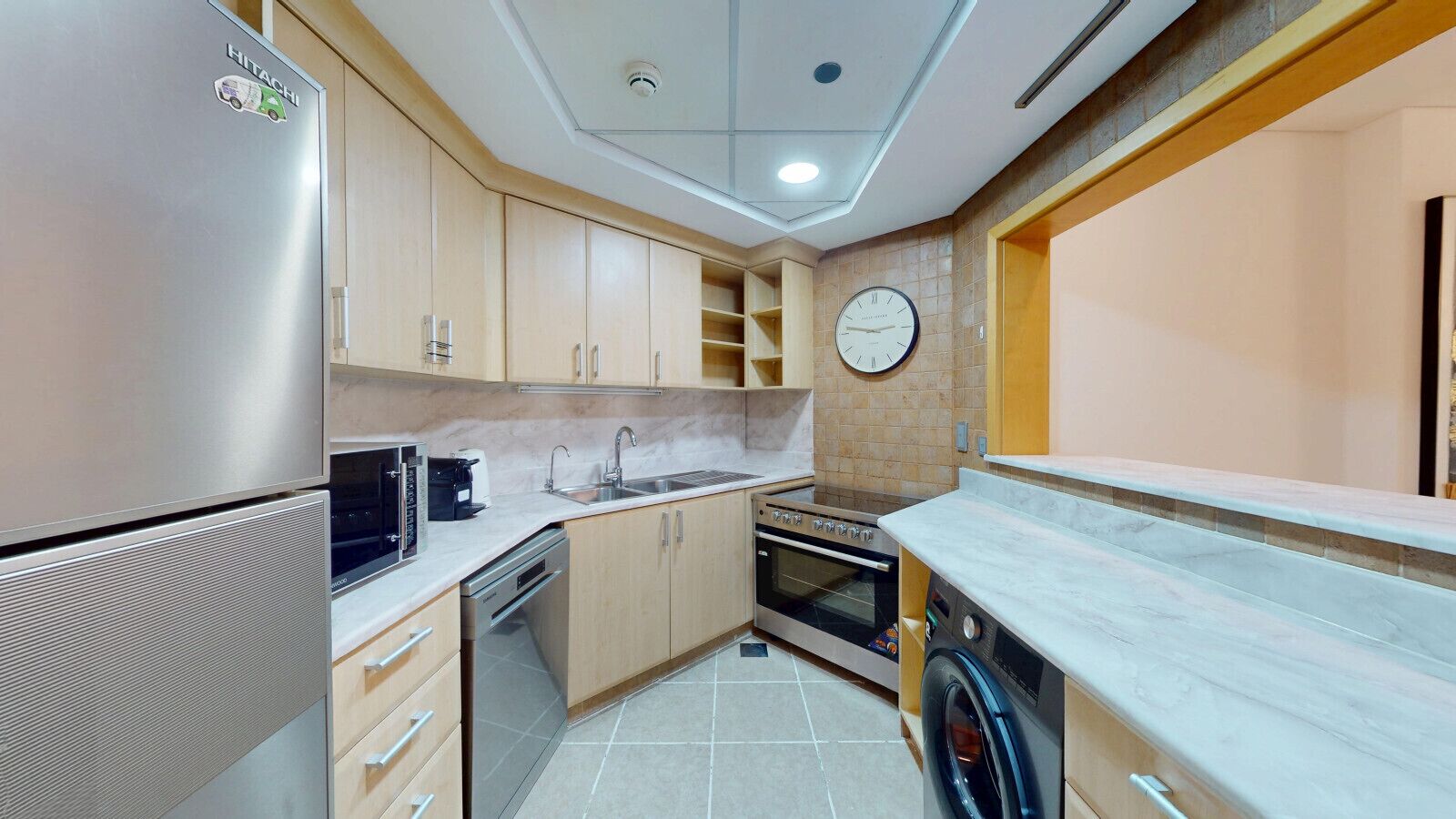 Eine kompakte Küche mit Kühlschrank, Mikrowelle, Backofen und Waschmaschine.