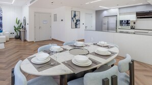 Un comedor moderno con una mesa redonda dispuesta para seis personas, rodeada de sillas tapizadas en gris claro.