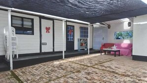 A covered outdoor area with a brick floor, white walls, and a red bow decoration on the door. - CASA VILLA LUZ (Tuta)