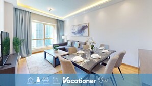 A modern living room with a dining area, large windows, and a flat-screen TV.
