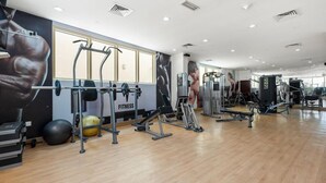A spacious gym with various exercise equipment, a large mirror, and motivational posters on the walls.