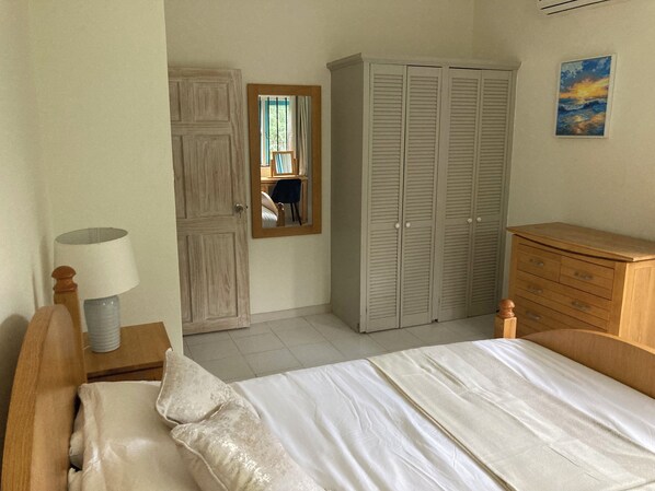 Un dormitorio con una cama, un aparador de madera, un armario, un espejo y una lámpara.