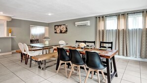 A dining area with a glass table, black chairs, and a wooden bench. - Spacious Villa with Heated Pool, Trampoline, BBQ, Tennis, Air Hockey (Hollywood)