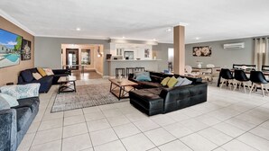 A spacious living room with a large black leather sofa, a coffee table, and a dining area with a white table and black chairs. - Spacious Villa with Heated Pool, Trampoline, BBQ, Tennis, Air Hockey (Hollywood)