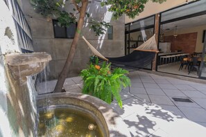 A courtyard with a water feature, a hammock, and a dining area visible through the glass doors. - Casa de Cobre (Oaxaca)
