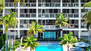 Ett hotell med en swimmingpool omgiven av solstolar och palmer.