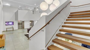 A modern staircase with wooden steps and a glass railing, leading to an upper level. - Charming LOFT - Downtown CL - Rooftop - BBQ - Playhouse Sq - Pets OK - Parking (Cleveland)
