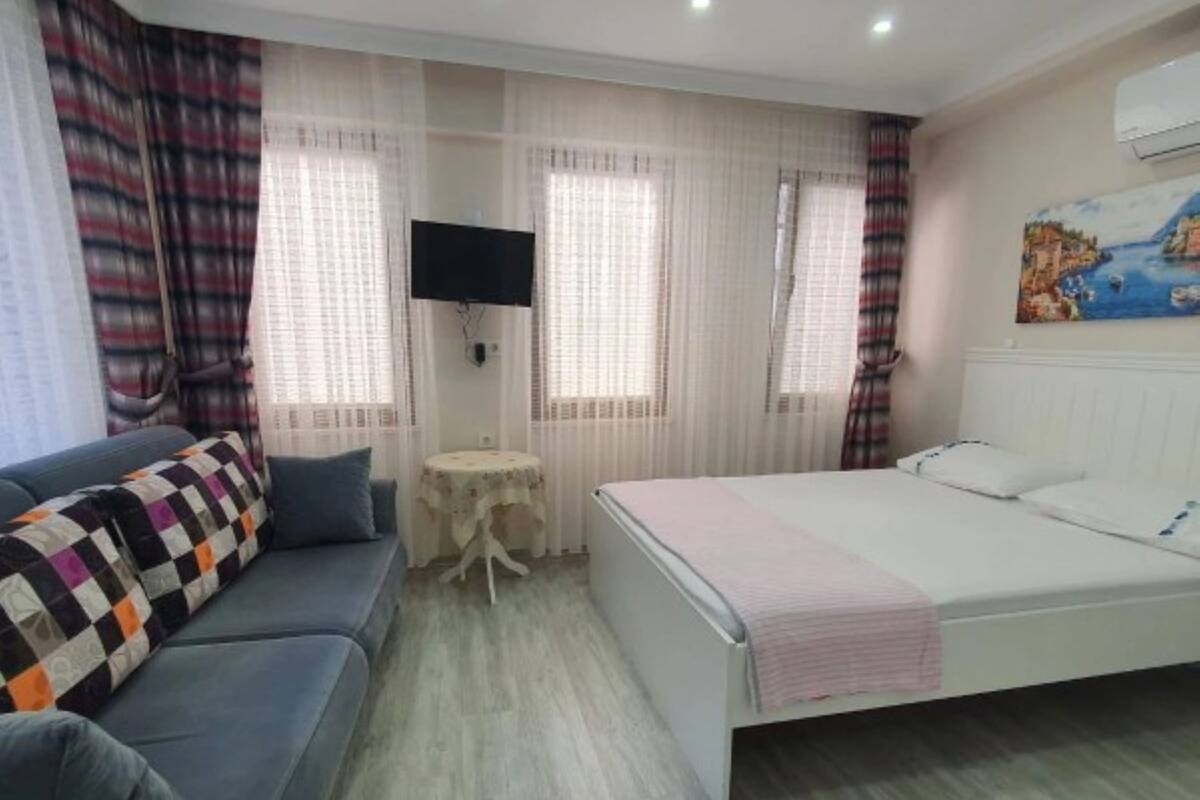 A bedroom with a bed, a sofa, a small table, and a TV.