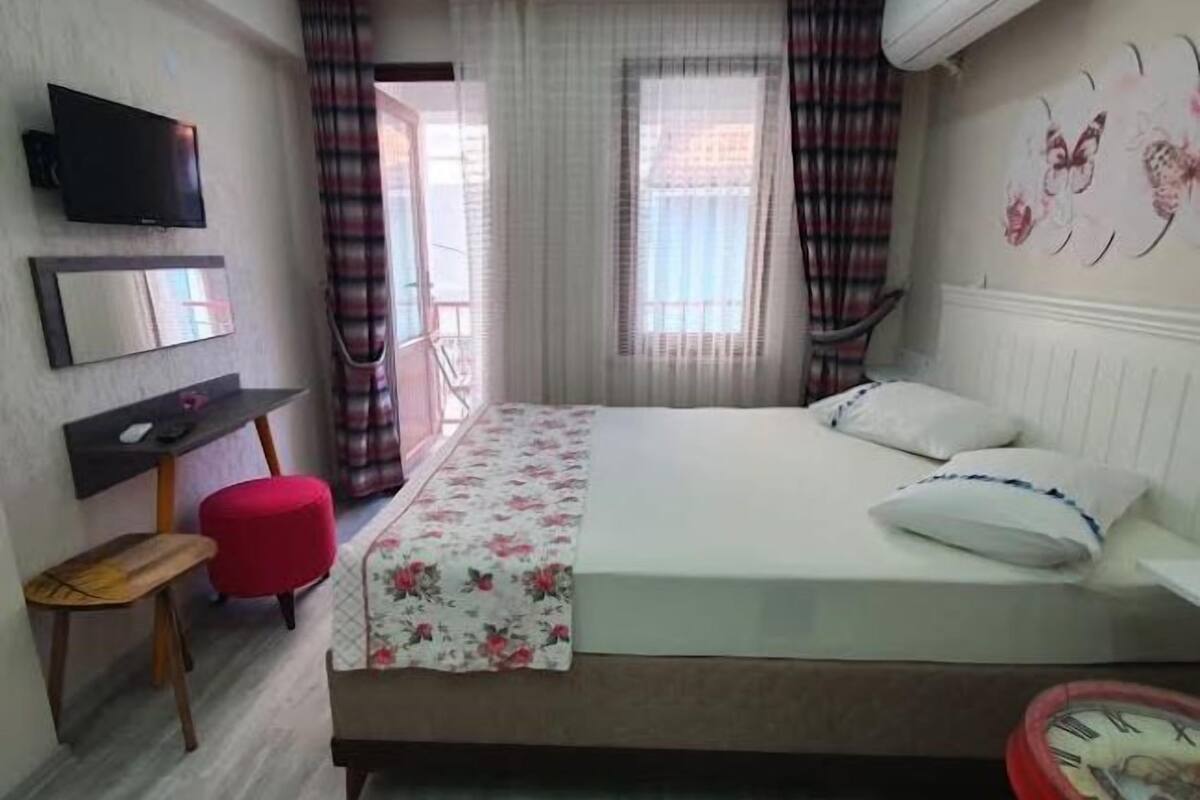 A bedroom with a bed, a TV, a desk, and a chair.