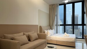 Una habitación de hotel moderna con sofá, cama, una mesita y un ventanal grande con vista a la ciudad.
