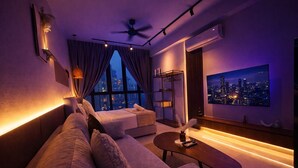 Un salon moderne avec un canapé, une table basse, un téléviseur et une vue sur la ville.