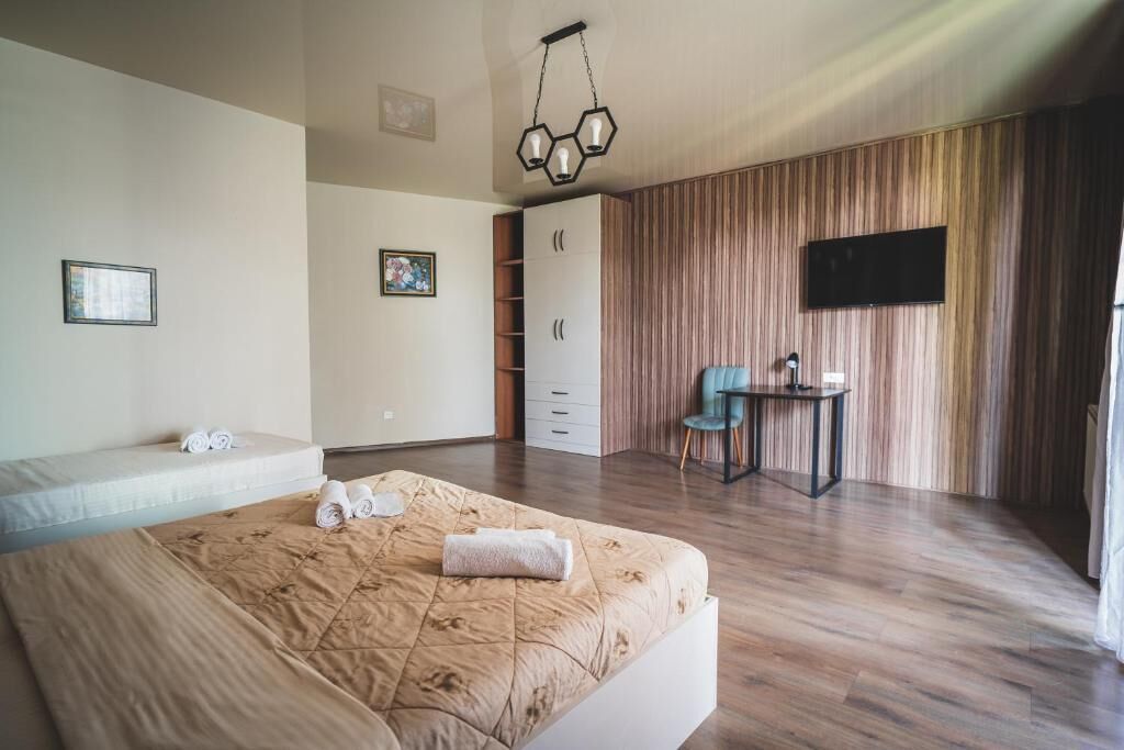 Un dormitorio moderno con una cama grande, un escritorio, un armario y una televisión montada en la pared.