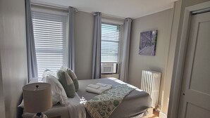 Un dormitorio con una cama, una mesita de noche con lámpara y un radiador.