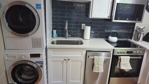 Una cocina compacta con lavadora, un lavabo, una estufa y armarios.