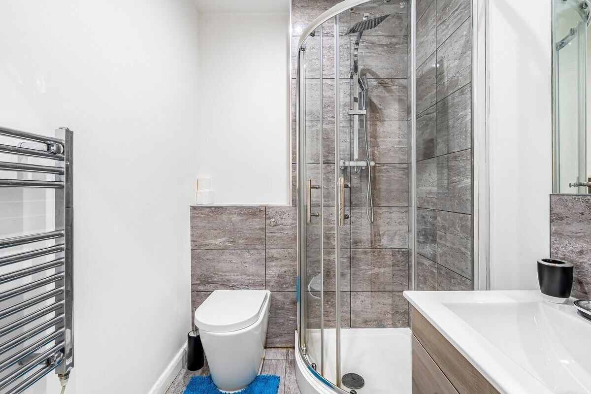 Un baño moderno con ducha de vidrio, inodoro blanco y tocador de madera.