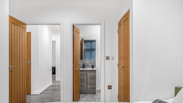 A hallway leading to a bathroom with a sink and mirror. - The Azure Hideaway 2BR 2BA City Centre (Leicester)