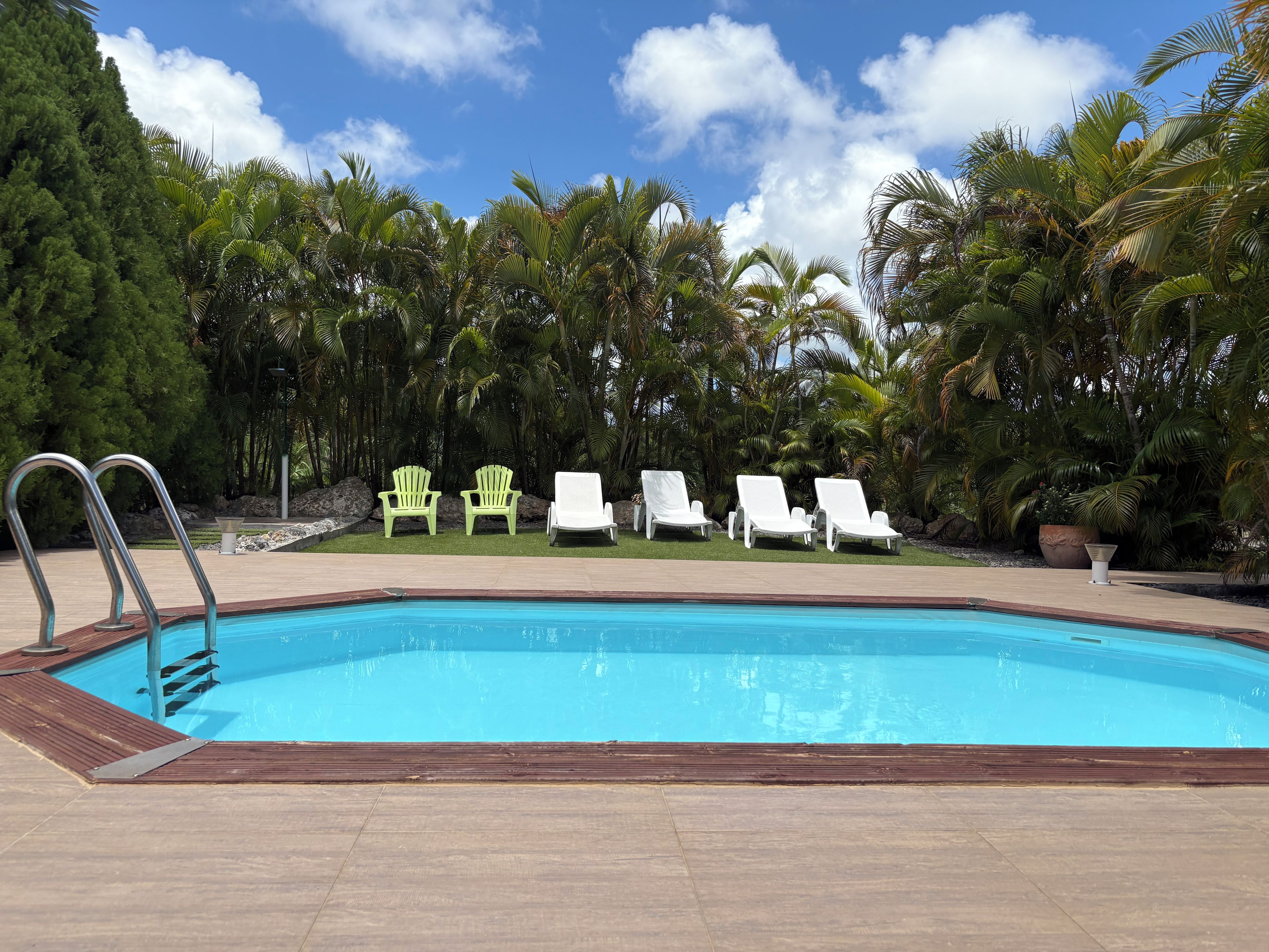 A swimming pool with lounge chairs and a metal ladder.
