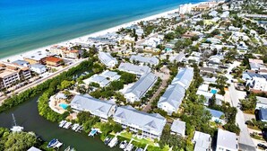 An aerial view of a coastal residential area with a marina, beachfront, and dense housing.