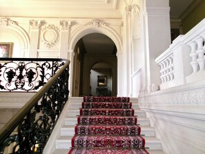 Eine prächtige Treppe mit aufwendiger Geländerarbeiten und einem gemusterten Teppich.