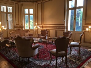 Ein Zimmer mit einem roten Teppich, verzierten Stühlen und einer Chandelüster.