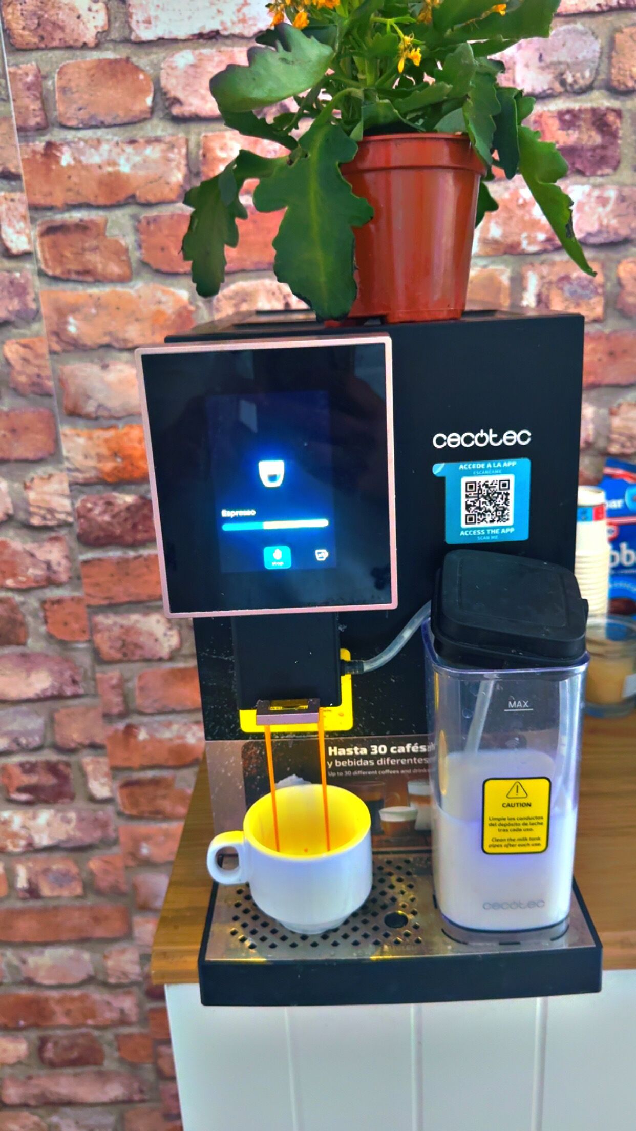 Eine Kaffeemaschine mit digitalem Display, einem QR-Code für den App-Zugriff und einer Kaffeetasse.