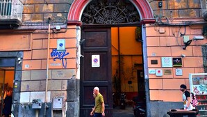 A building with a large arched entrance, a sign for a medical center, and a street vendor outside. - هوستيل دولشي دي مونيكا نابوليتنا (Napoli)