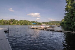 Un lago tranquillo con un pontile, barche e un pendio boscoso sullo sfondo.