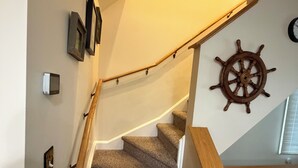 Een trap met beklede treden, houten leuningen en een decoratie van een roer op de muur.