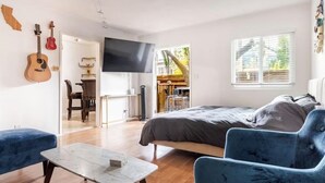 A room with a bed, a TV, a guitar, and a dining area. - Charming Pied-e-terre near the beach for a relaxing getaway (Los Angeles)