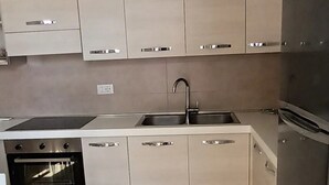 Una cocina moderna con armarios de color claro, un refrigerador de acero inoxidable y un horno empotrado.