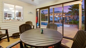 A dining area with a round table and chairs, a ceiling fan, and a view of a pool and outdoor seating area. - Canal front, Heated pool, Boat lift, Pet friendly (Gulf Breeze)
