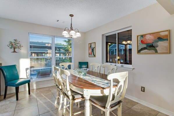A dining area with a wooden table, white chairs, and a chandelier.