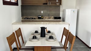 Cocina compacta con mesa, sillas, refrigerador y estufa.