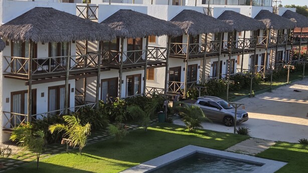 Un hotel con varios balcones, piscina y aparcamiento.