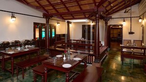 A dining area with wooden tables and benches, a high ceiling with exposed beams, and hanging lanterns. - MALABAR KOVILAKAM (Tirurangadi)