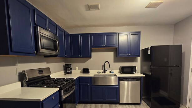 Una cocina moderna con armarios azules, electrodomésticos de acero inoxidable y piso de madera.
