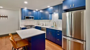 A modern kitchen with blue cabinets, stainless steel appliances, and a white island.
