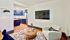 A modern living room with a round coffee table, a white sofa, and a TV mounted on the wall.
