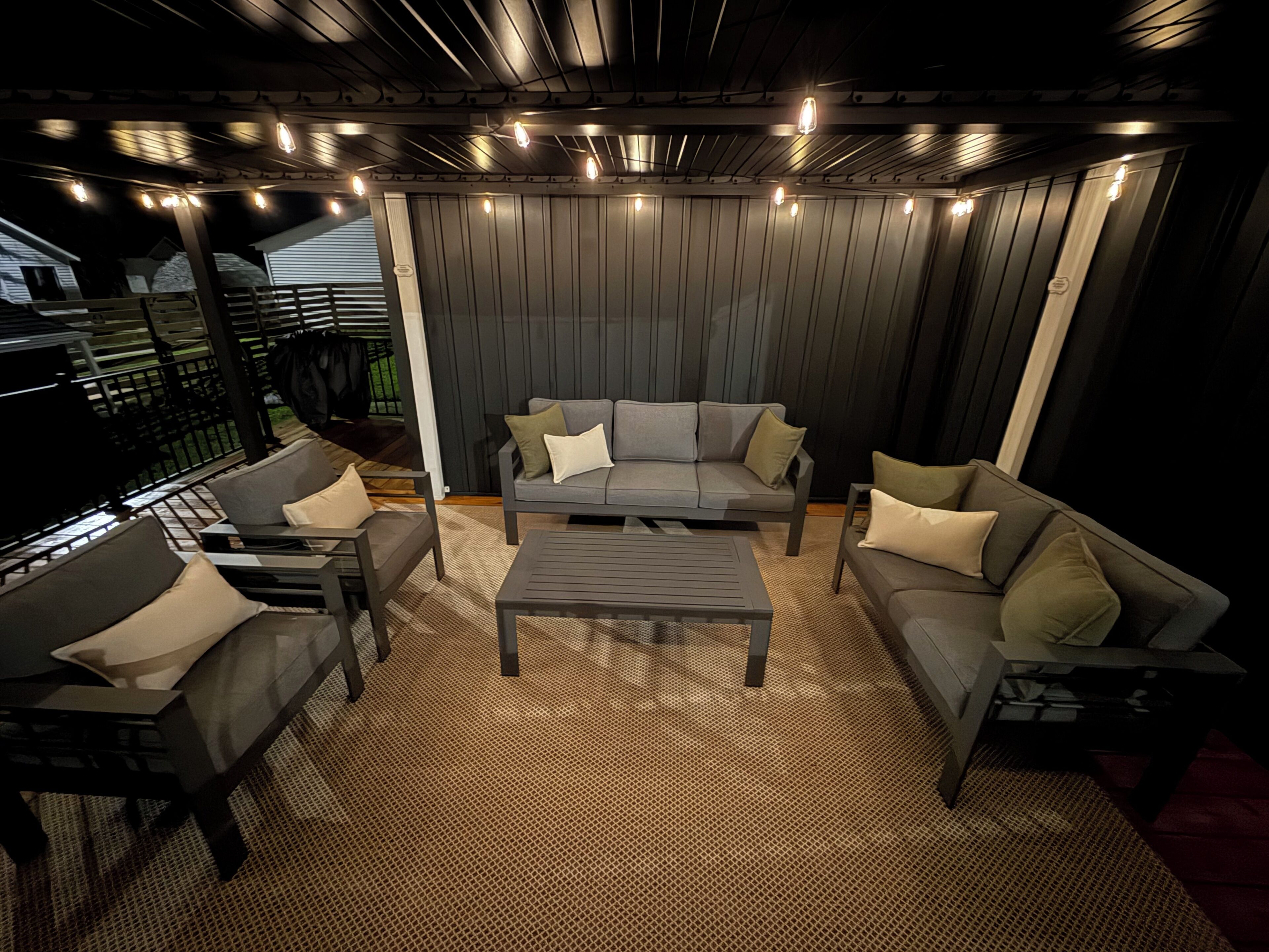 An outdoor seating area with a sofa set, a coffee table, and a patterned rug.