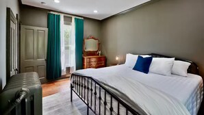 A bedroom with a bed, a dresser, a mirror, and a suitcase.