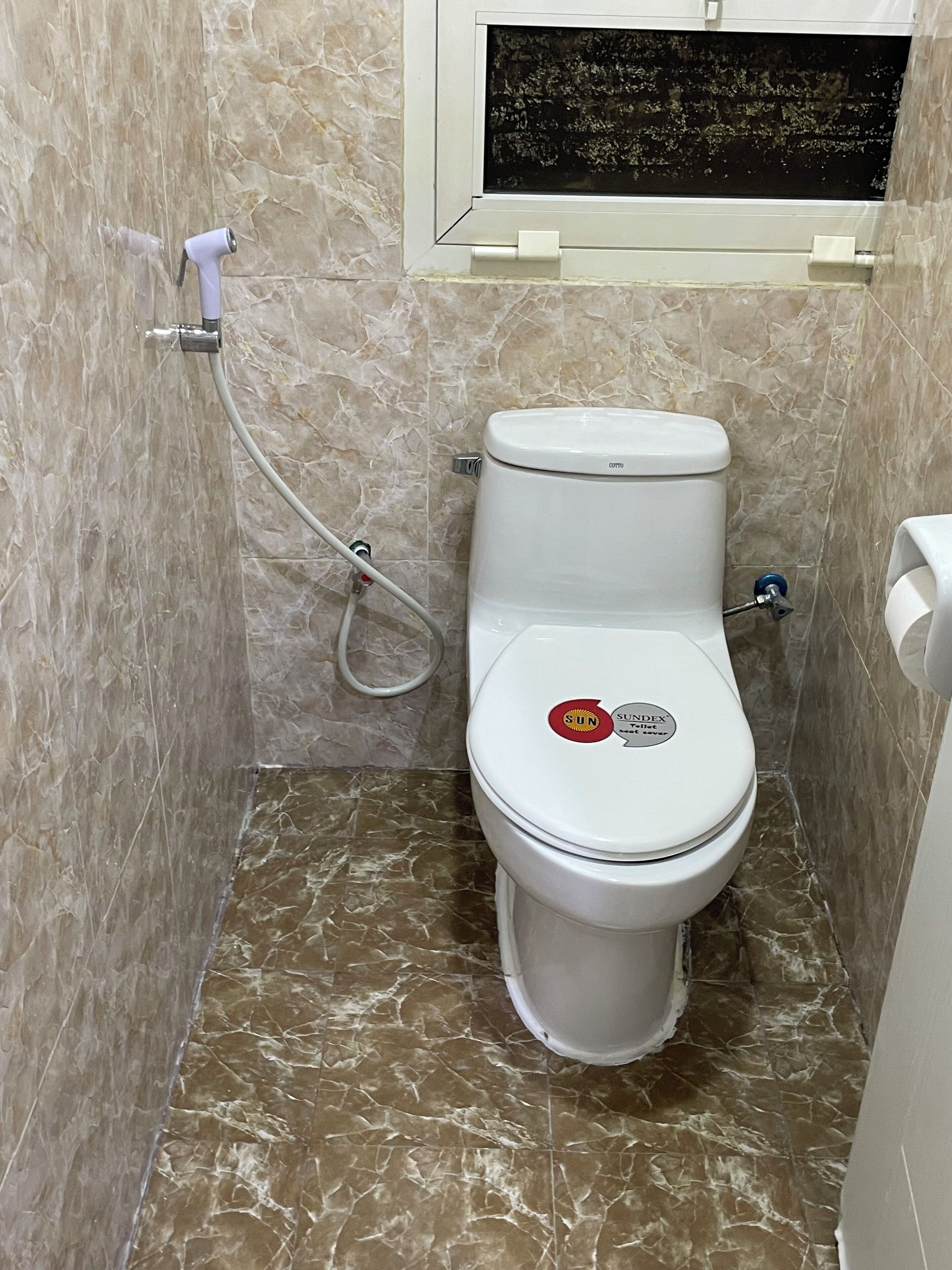 Een badkamer met toilet, douche en een marmeren vloer.