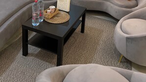 En moderne stue med en grå sofa, et sort sofabord og et stort vindue med diamantmønstret glas.