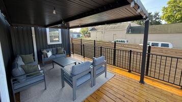 Un espace extérieur abrité, doté d’une terrasse en bois, d’un canapé et d’une table.