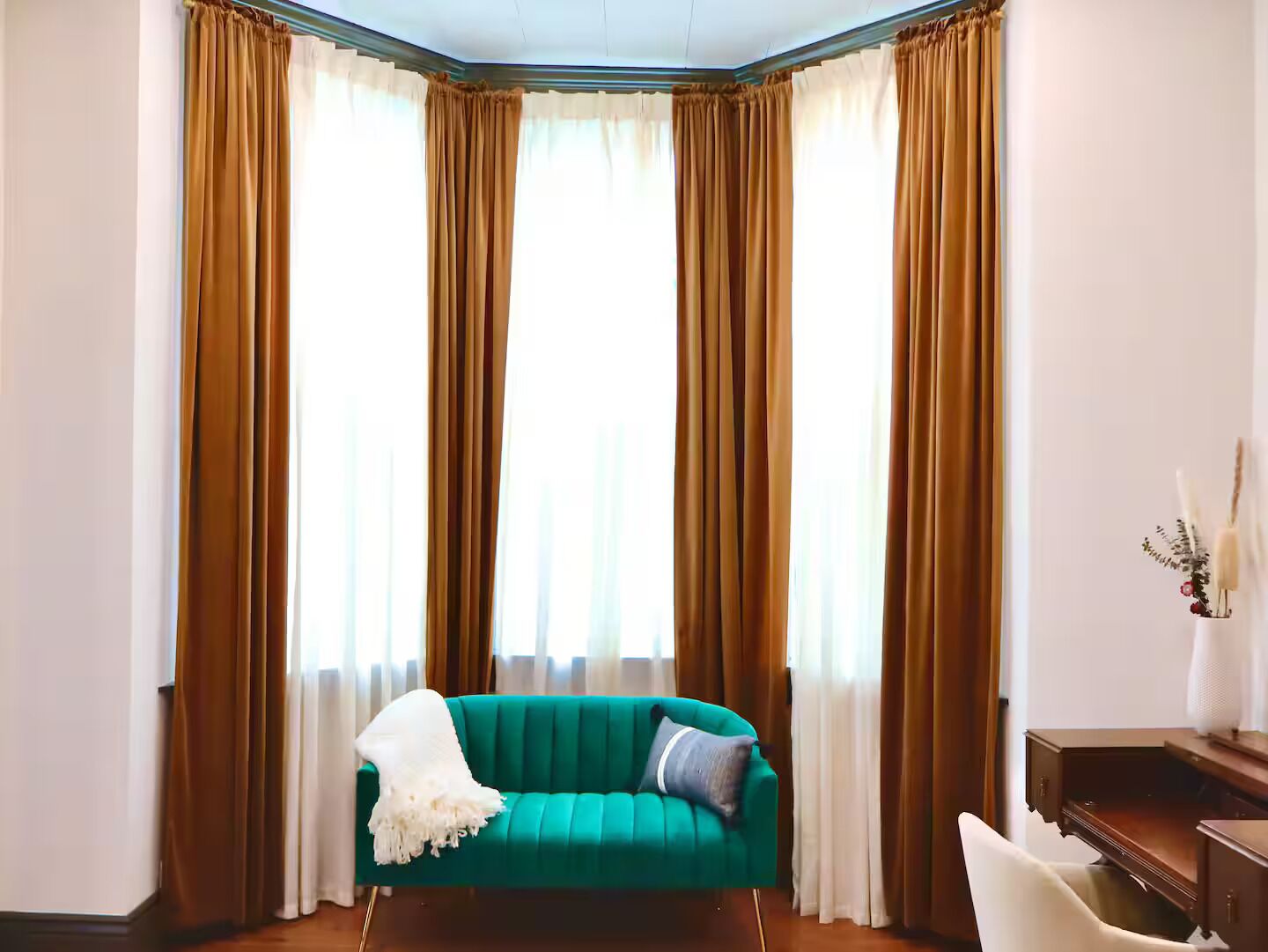 Ein Zimmer mit einem türkisfarbenen Sofa, einem weißen Sessel und einem Holztisch.