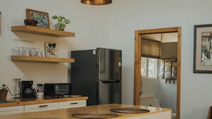 Une cuisine moderne avec des poutres en bois, un réfrigérateur noir, un four à micro-ondes et un îlot central en bois avec des tabourets.