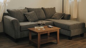 Un salon avec un canapé gris, une table basse en bois et des tableaux encadrés accrochés au mur.