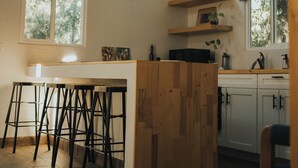 Une cuisine moderne avec des tabourets de bar en bois, des luminaires suspendus et une grande fenêtre qui laisse entrer la lumière naturelle.