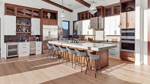 A modern kitchen with a central island, bar stools, and built-in appliances.