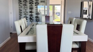 Un coin repas avec une table à plateau en verre, des chaises à revêtement blanc et un ventilateur de plafond.