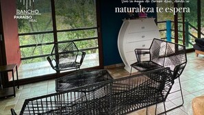 A modern interior with black metal furniture, large windows offering a view of greenery, and contact information for Rancho Paraíso Real. - Rancho Real Paraiso (Amealco)
